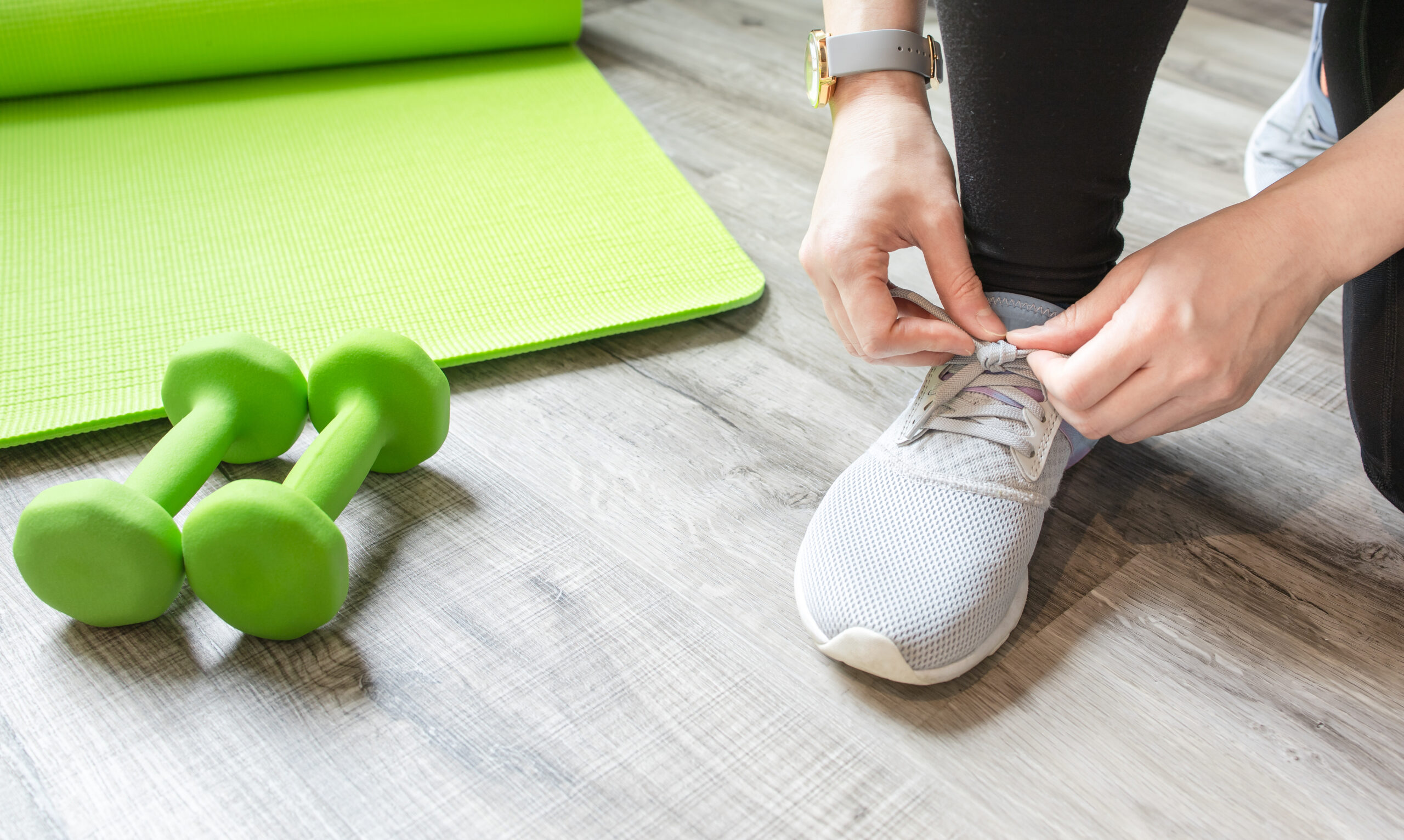 Woman tying shoelaces on sneakers in the gym.